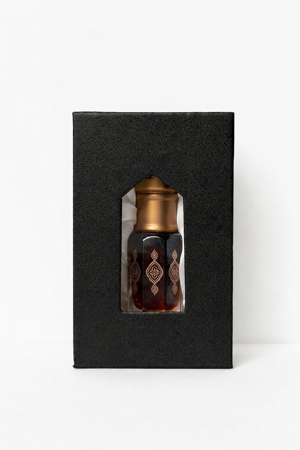 Bronze-colored bottle with a decorative design on a black box against a white background